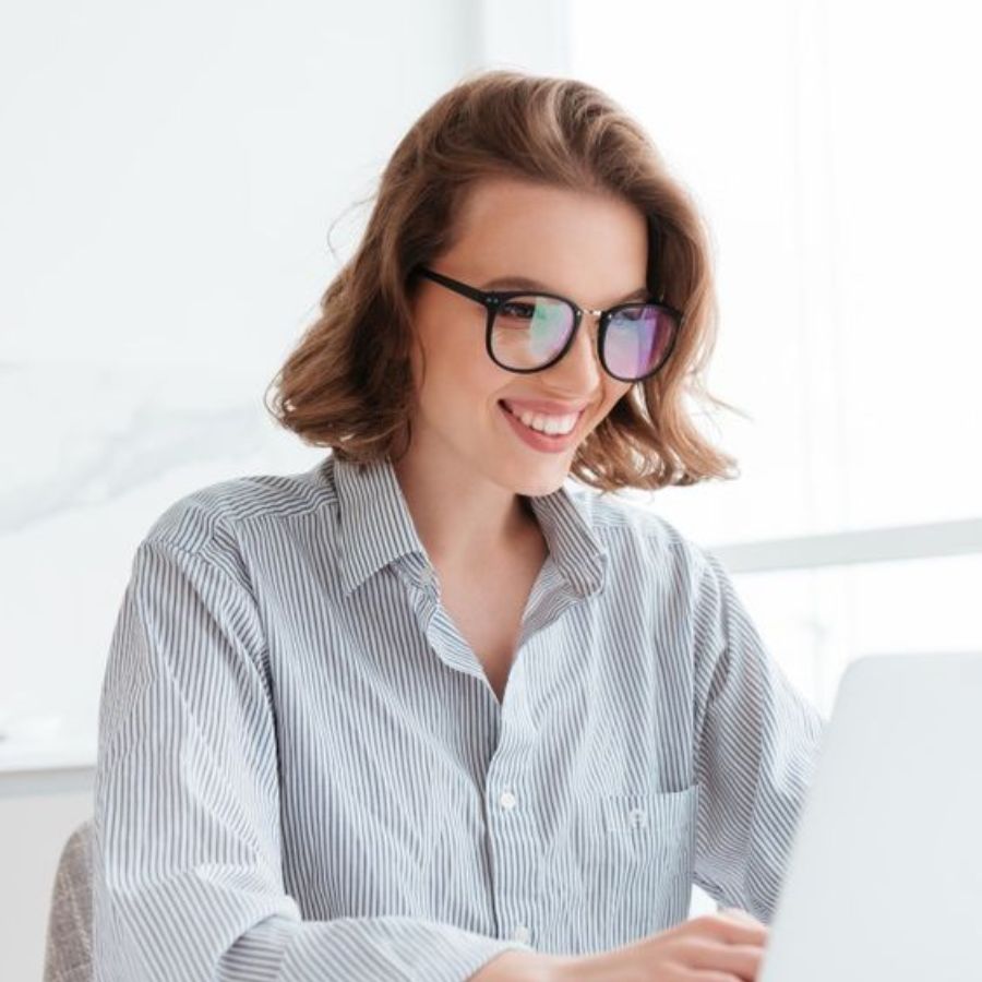Cô gái đang đeo kính đa tròng và làm việc trước máy tính