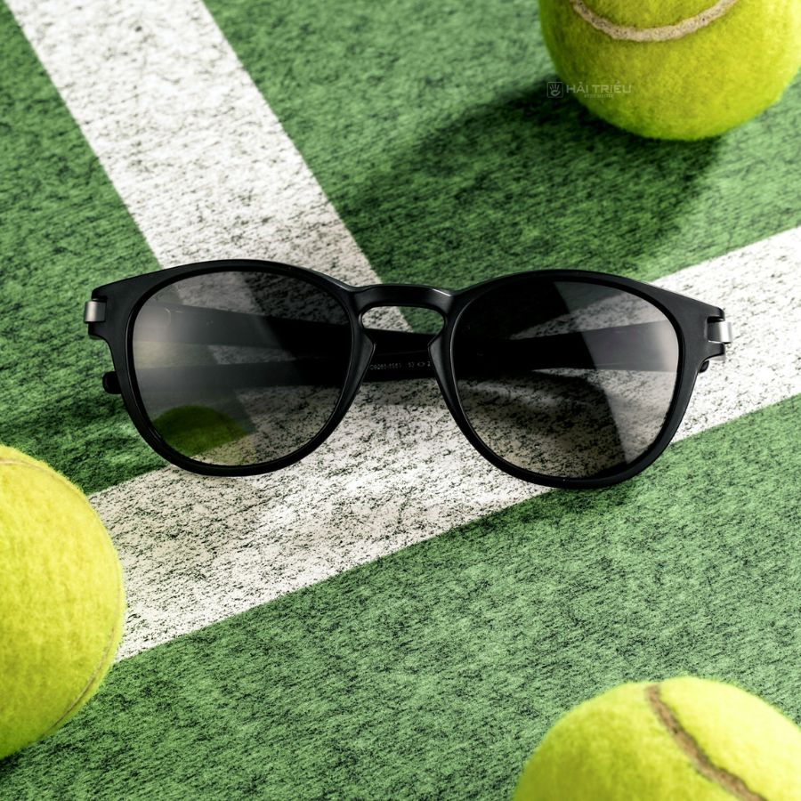 Chiếc kính râm đen được đặt trong nền sân tennis và những quả tennis xung quanh