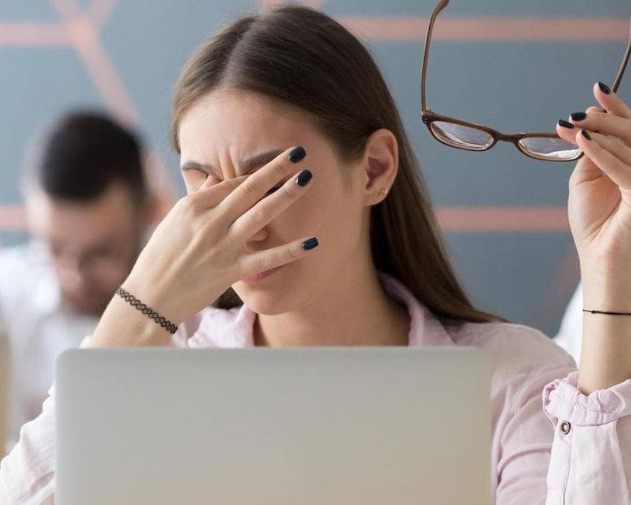 Người phụ nữ mỏi mắt, ôm trán căng thẳng khi làm việc trước máy tính
