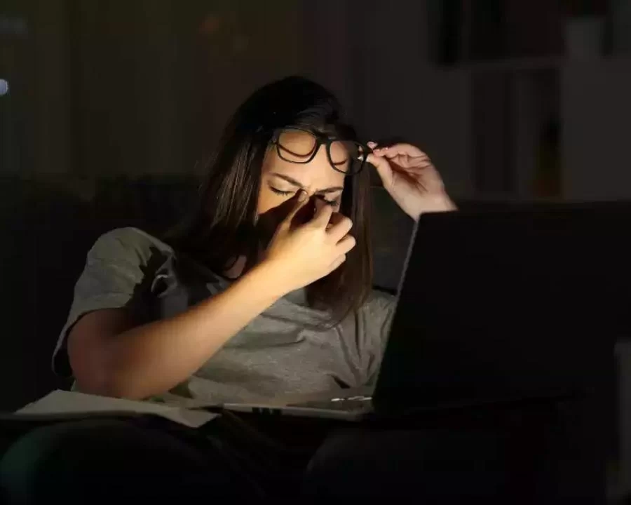 Hội chứng thị giác màn hình (CVS): Nguyên nhân, khắc phục (3) Người phụ nữ đang day mắt mệt mỏi trước màn hình máy tính trong điều kiện ánh sáng yếu